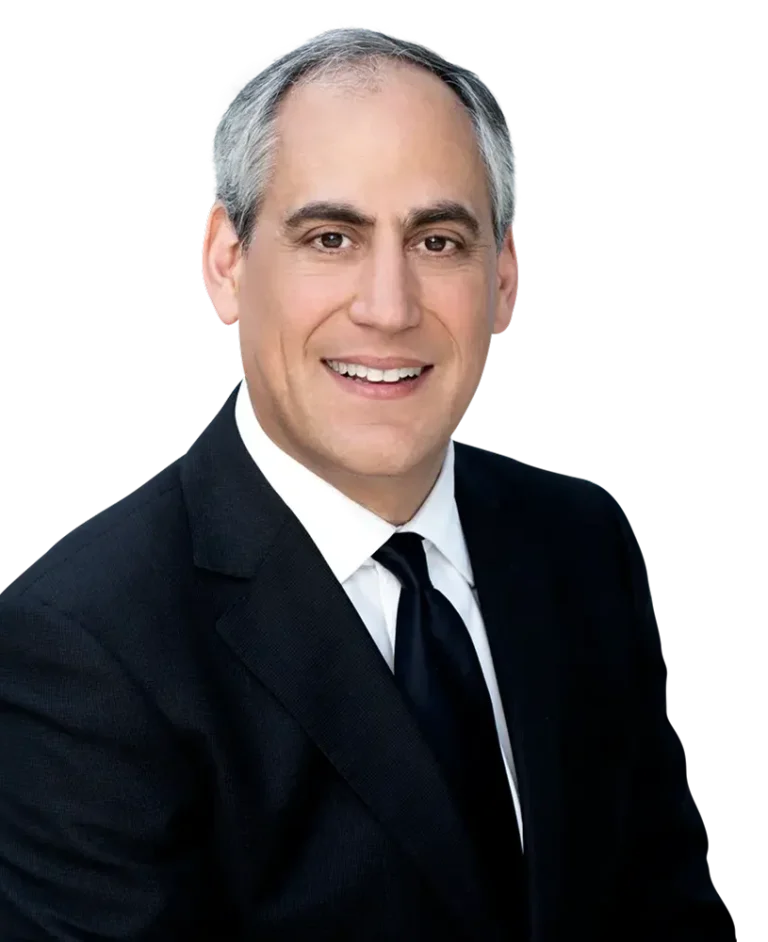 Smiling man in a black suit and tie against a plain background.