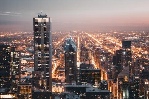 City skyline at dusk with illuminated streets and skyscrapers.