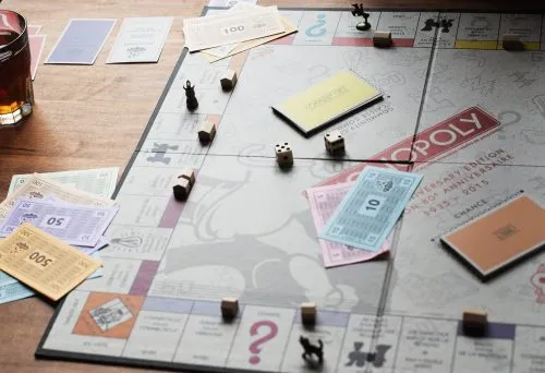 Monopoly board game setup with currency, cards, and tokens on a table.