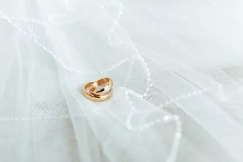 Two gold rings on white tulle with delicate bead trim.