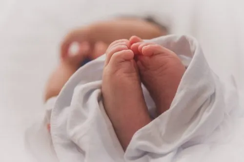 Close-up of a newborn's feet wrapped in a white blanket.