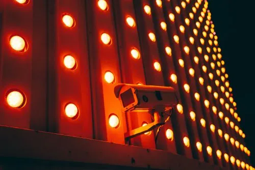 Security camera mounted on a wall with glowing red lights.