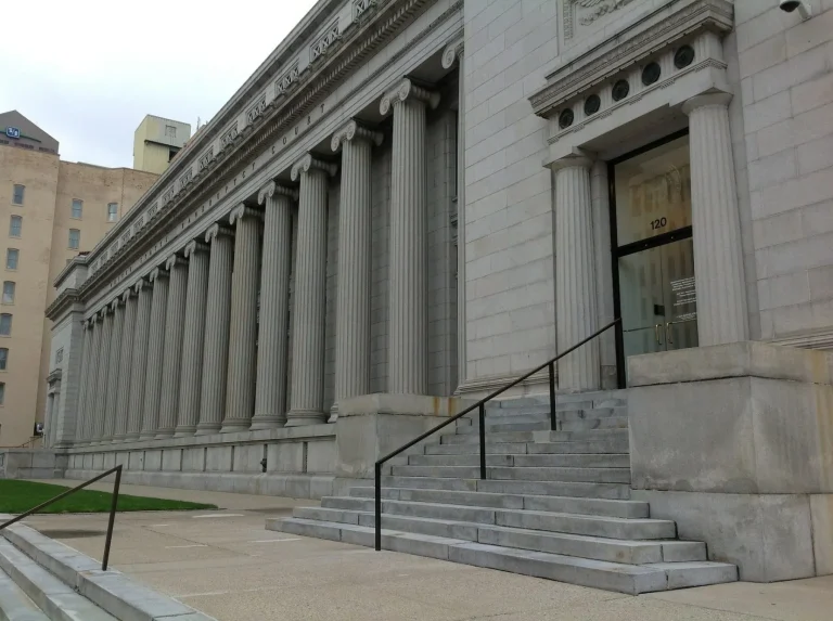 Stone building with tall columns and a staircase leading to a door.