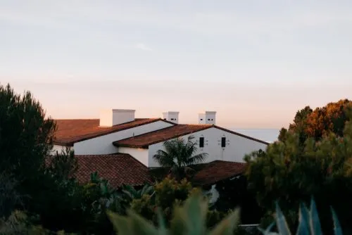 Tile-roofed house surrounded by trees at sunset.