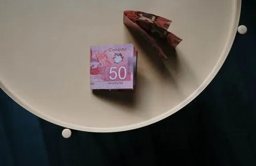 Stack and folded Canadian $50 bills on a round beige table.