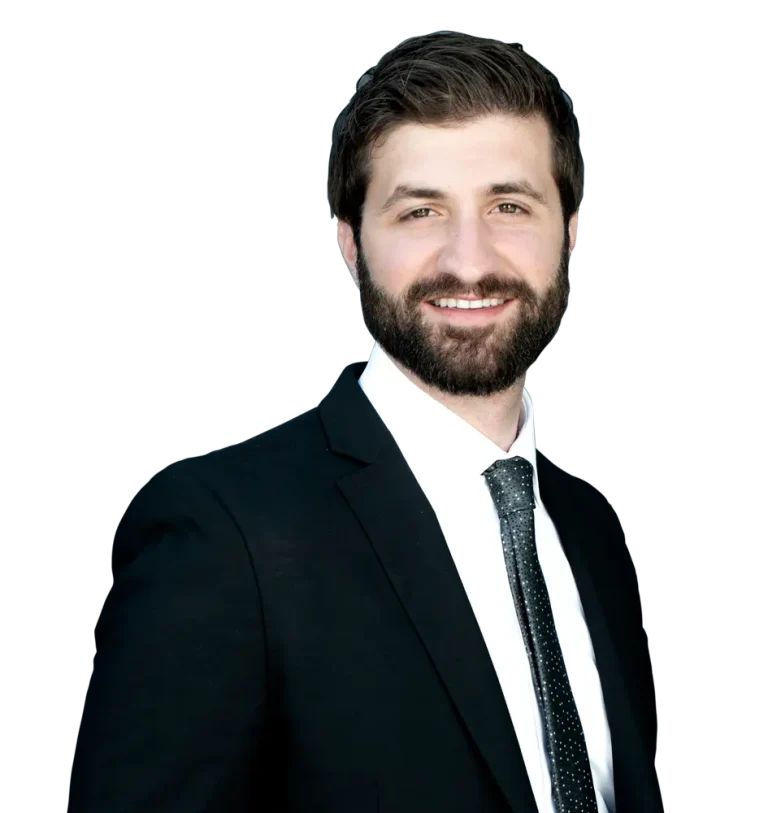 Man in a suit with a beard, smiling in front of a dark background.