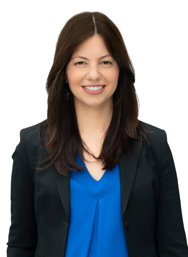 Smiling woman in a blue blouse and black blazer against a plain background.