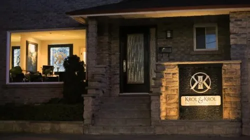 Exterior of a building entrance with a lit "Krol & Krol" sign and illuminated windows.