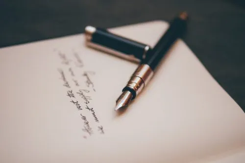 Fountain pen lies on a handwritten open notebook.