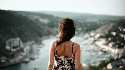 Woman in floral dress overlooking a scenic river valley.