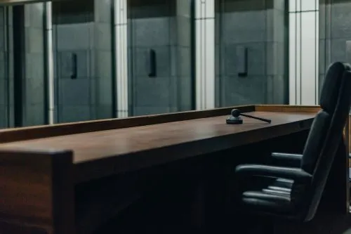 Empty judge's bench with gavel and chair in a courtroom.
