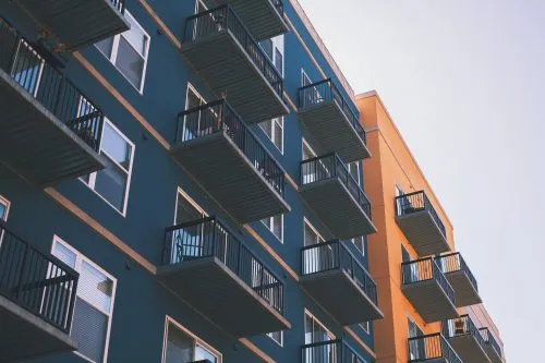 Modern building with blue and orange walls featuring rows of balconies.