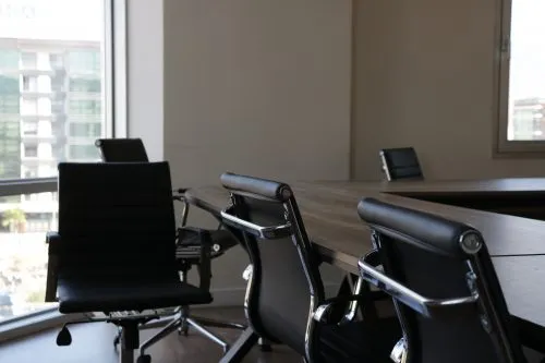 Empty conference room with black chairs around a wooden table.