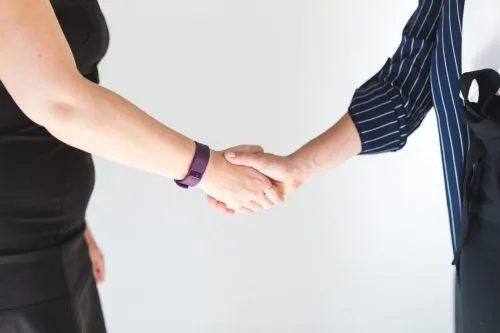 Two people shaking hands in a professional setting.