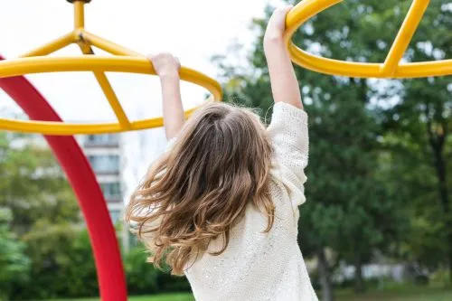 Child playing on circular monkey bars in a park.