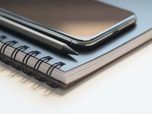 Smartphone and pencil on a spiral-bound notebook.