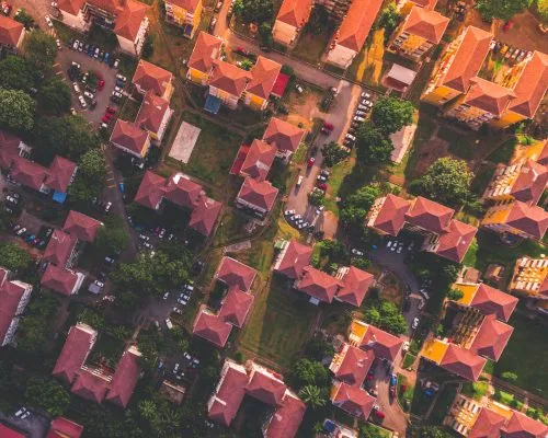 Aerial view of a residential area with red-roofed buildings and surrounding greenery.