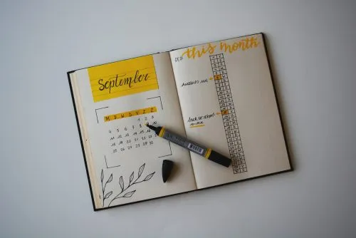Open planner with September calendar, habit tracker, and a black marker.