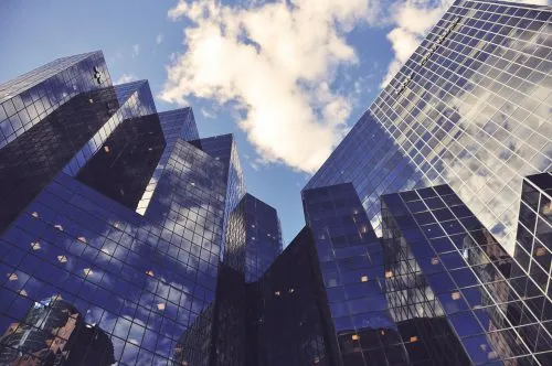 Reflection of clouds on glass skyscrapers against a blue sky.