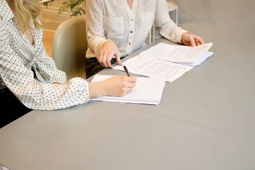 Two people in patterned shirts reviewing documents at a table.