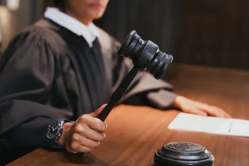 A judge holds a gavel in a courtroom setting.