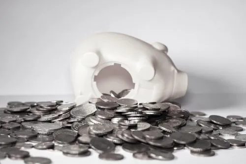 Empty piggy bank lying on its side with spilled coins.