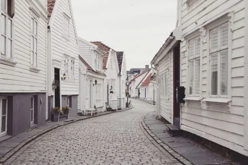 A narrow, cobblestone street lined with white wooden houses.