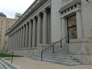 Stone building with tall columns and a staircase leading to a door.