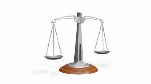 A balanced metal scale with a wooden base against a plain background.
