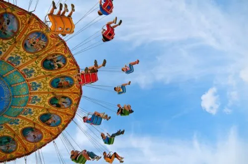 Colorful swing ride against a blue sky with people enjoying the ride.