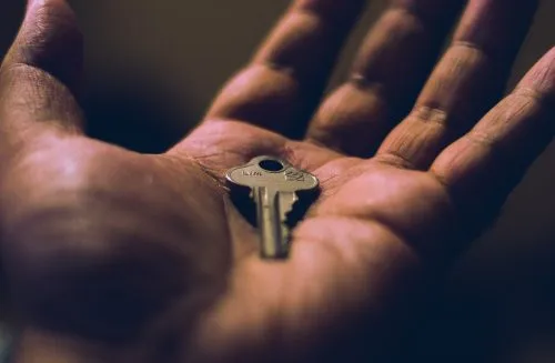 A key resting in the palm of an open hand.