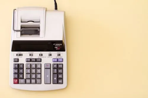 A white printing calculator on a yellow background.