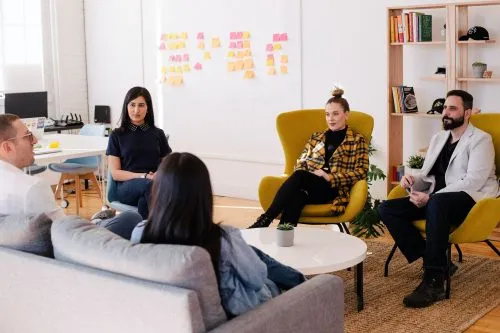Five people sitting in a casual office setting having a discussion.