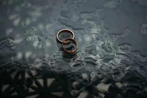 Two gold rings on a wet, textured surface.