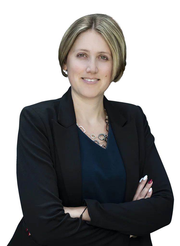 Person with short hair in a black blazer, arms crossed, smiling at the camera.